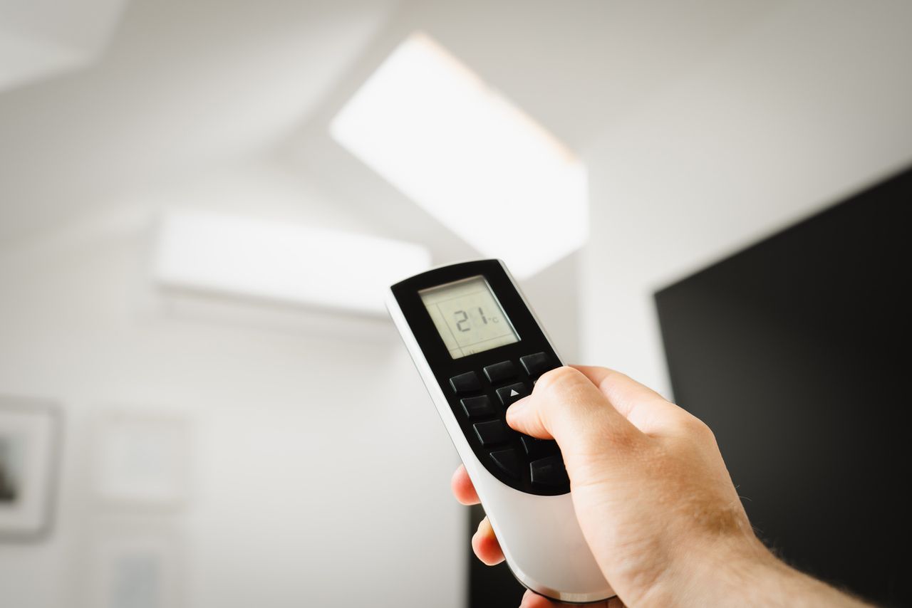 Nos services Close-up of a man using a remote to control air conditioning indoors.