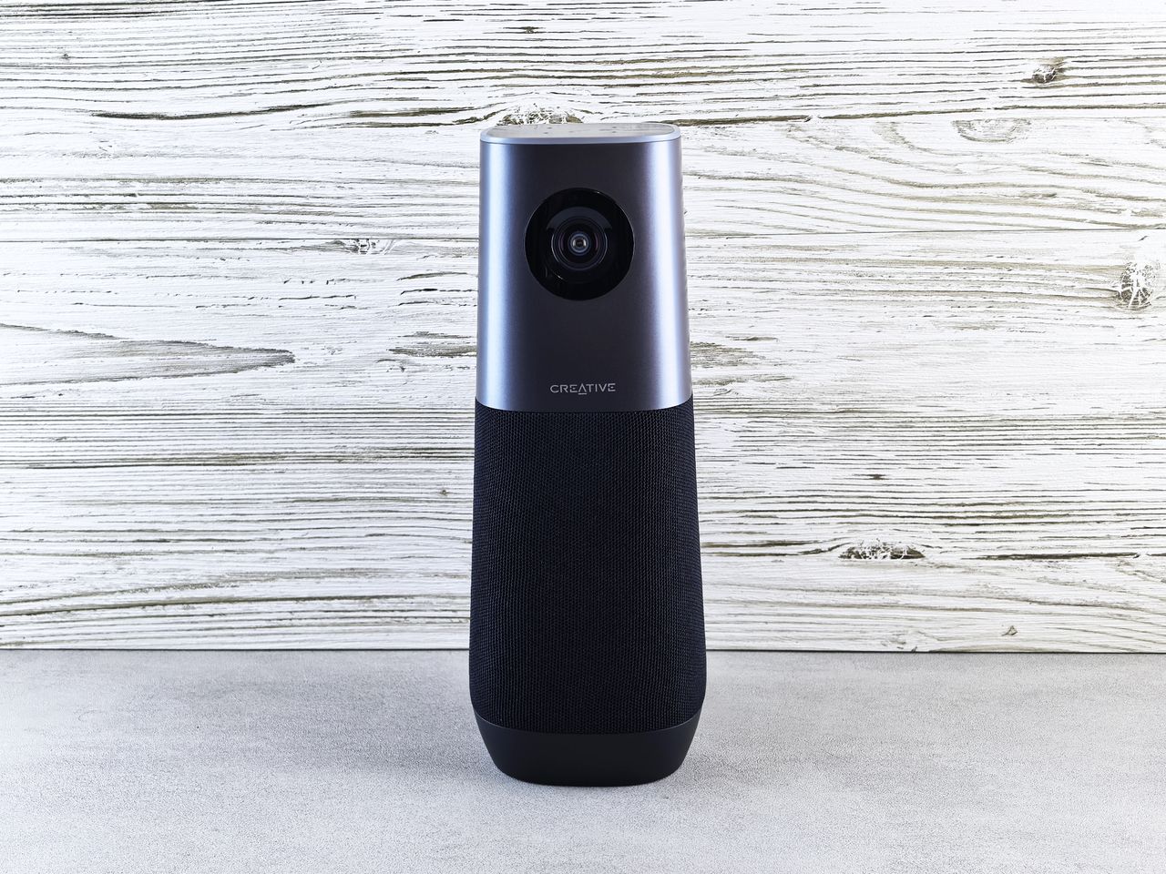 Nos services A sleek smart speaker with an integrated camera against a wooden backdrop, perfect for modern tech setups.