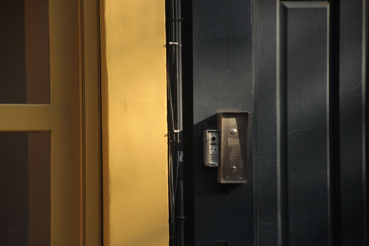 Nos services A close-up view of a dark door with a yellow frame and a metallic intercom system.