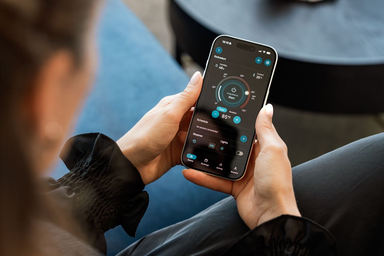 Mastering the First Impression: Your intriguing post title goes here A woman controls a smart sauna system via a touchscreen app on her smartphone indoors.